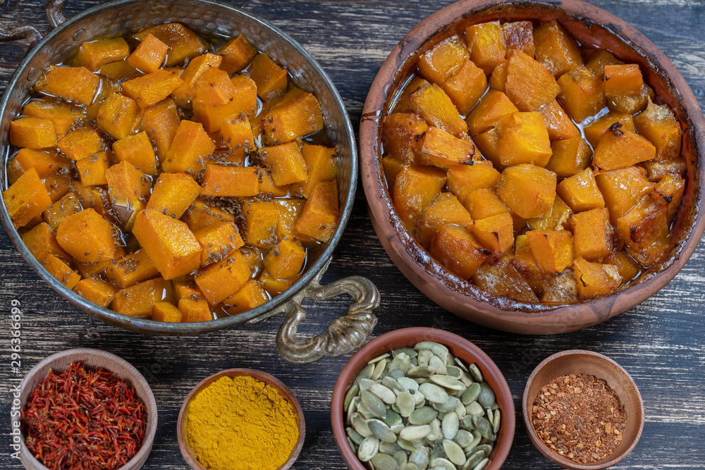 Baked yellow pumpkin with honey, anise, olive oil and spices on a plate on the wooden table. Vegetarian food. Closeup Baked yellow pumpkin with honey, anise, olive oil and spices on a plate on the wooden table. Vegetarian food. Closeup