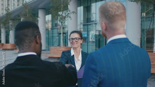 Attractive confident happy boss businesswoman smiles and sais thanks to her male diverse subordinates. Multiracial colleagues of success start-up photo