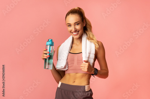 Smiling Girl Standing Holding Bottle Of Water, Studio Shot
