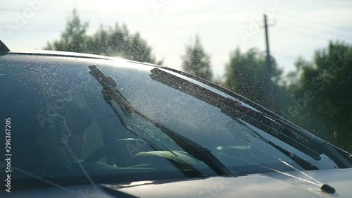 Closeup of windshield and wipers. Windshield washer on. Slow motion.