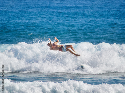 Fotografie Surfer in wave wipes out and falls off surf board.