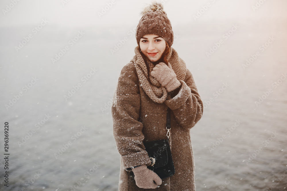 young and merry girl standing in the winter park near water young and merry girl standing in the winter park near water