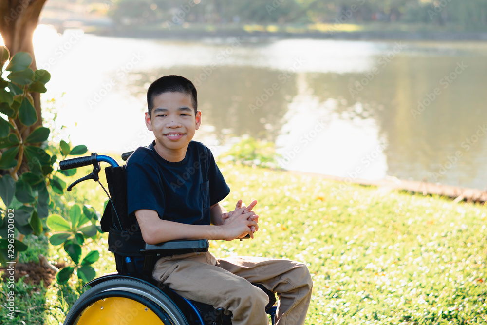 Fototapeta premium Disabled child on wheelchair is playing, learning and exercise in the outdoor city park like other people,Lifestyle of special child,Life in the education age of children,Happy disability kid concept.
