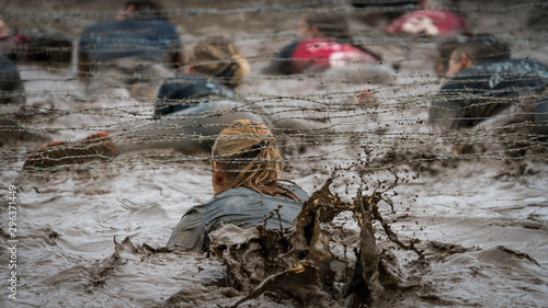 A woman crawling under barbed wire at a mud run  photo