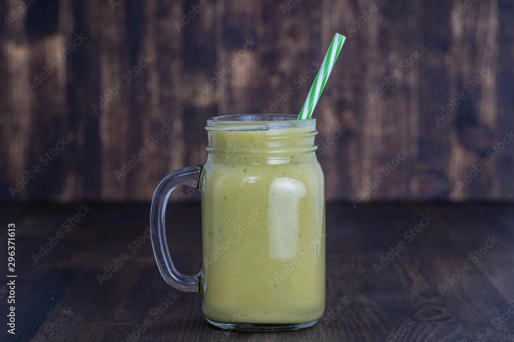 Fresh green smoothie from avocado, kiwi, banana and honey in glass mug on wooden background, closeup. Concept of healthy eating Fresh green smoothie from avocado, kiwi, banana and honey in glass mug on wooden background, closeup. Concept of healthy eating