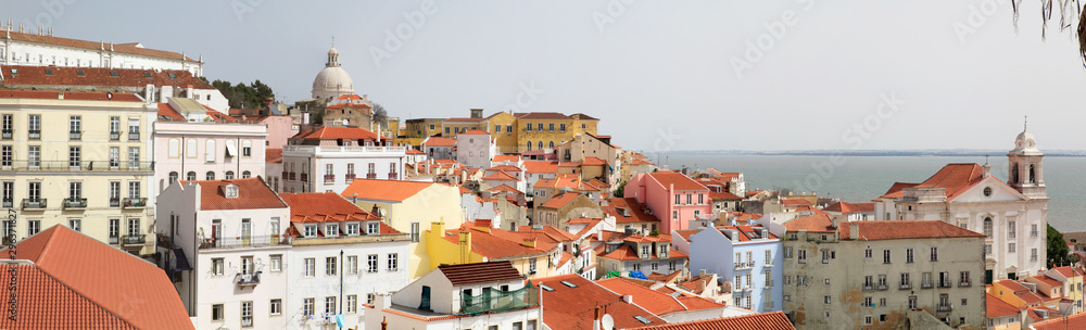 View of the city of Lisbon, Portugal. Summer sunny day, the sun on urban buildings, houses, buildings. Blue sky.