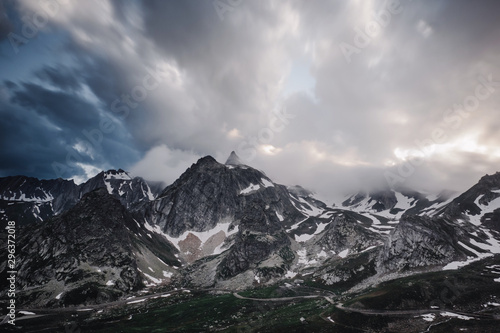 Snow covered barren mountains and storm clouds photo