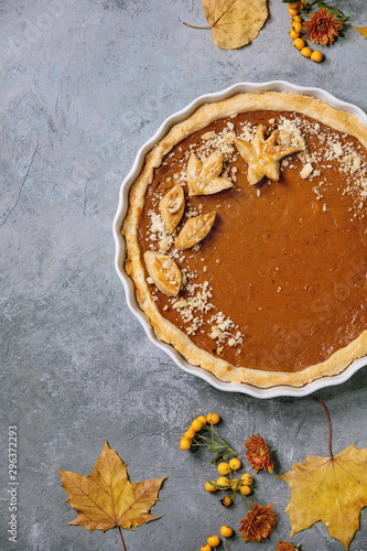 Photos Traditional homemade autumn pumpkin pie for Thanksgiving or Halloween dinner served in ceramic dish with yellow autumn leaves over grey texture background