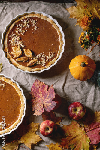 Wallpaper Mural Traditional homemade autumn pumpkin pies for Thanksgiving or Halloween dinner served in ceramic dish with yellow autumn leaves, pumpkins and apples on linen table cloth. Dark rustic style. Flat lay Torontodigital.ca