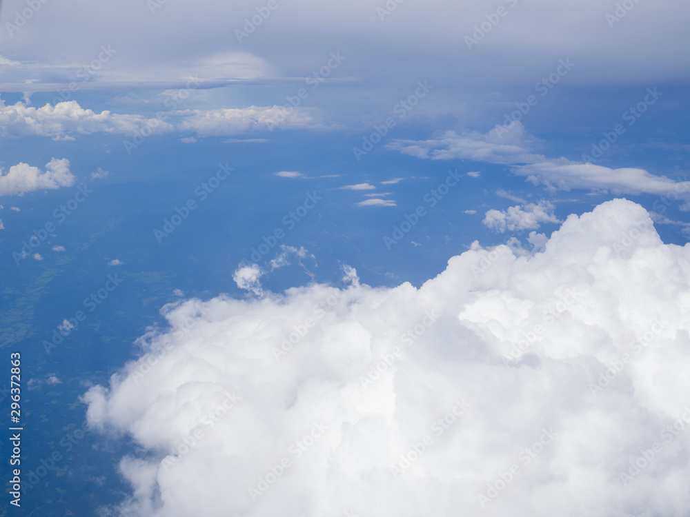Clouds from airplane window with blue sky and high angle ground
