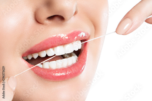 Young beautiful woman is engaged in cleaning teeth. Beautiful smile healthy white teeth. A girl holds a dental floss. The concept of oral hygiene. Promotional image for a dental clinic.