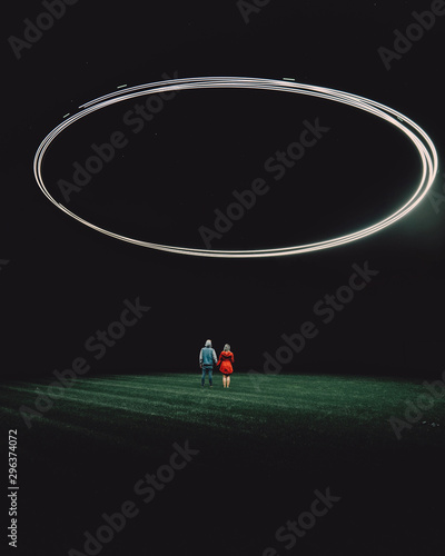 Couple standing on grassy field against light painting photo