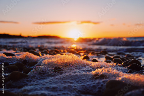 Close up of sea foam on beach at sunset