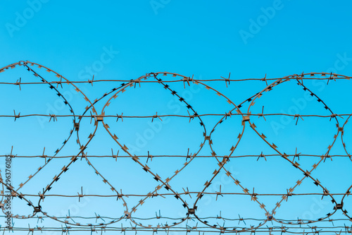 Several rows of woven barbed wire against a  clear blue sky. War and peace, prison and freedom, protection concept photo