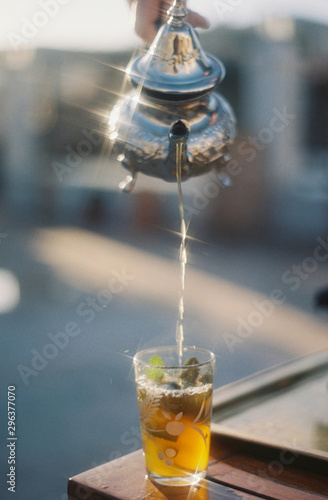 Person pouring mint tea from teapot into glass