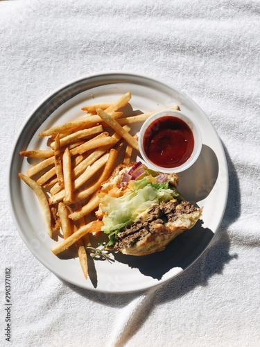 Overhead view of half eaten burger and french fries on plate