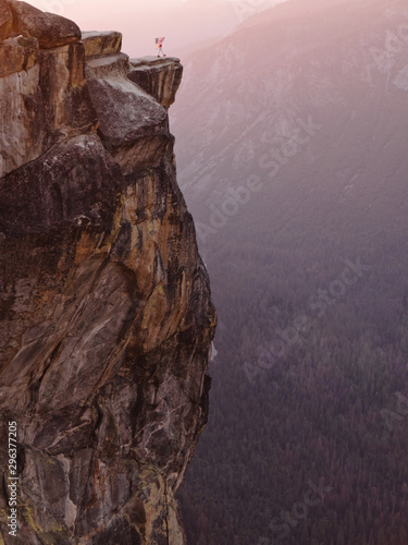 Person with American flag on top of cliff at sunset