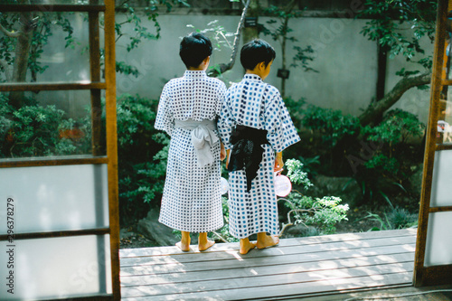 Rear view of siblings in kimono standing on patio
