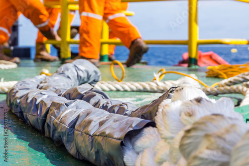 Offshore worker preparinf hawser rope for anchor mooring to platform jacke leg