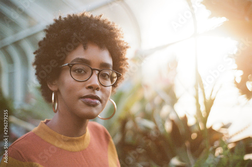 Portrait of young woman with glasses in greenhouse