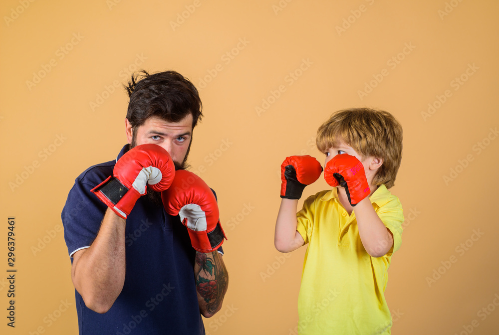 Father is training his son boxing. Little boy in boxing gloves working out with coach at gym