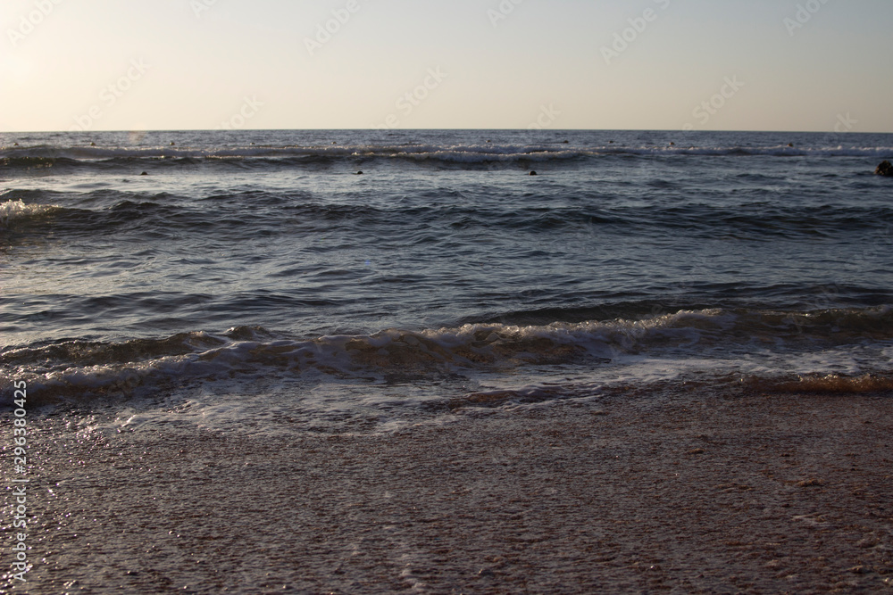 Summer background of hot sand with sea or ocean wave bubbles with copy space for card or advertisement at dawn or sunset