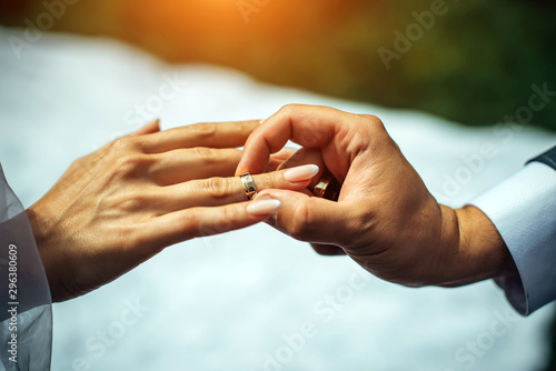 Groom put gold wedding ring on the bride's finger, close-up. The wedding ceremony, exchange of rings.