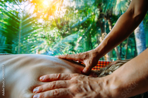 Acupressure massage in spa centre outdoor. Woman at acupressure back massage, masseur's hands close up. Body therapy for healthy lifestyle.