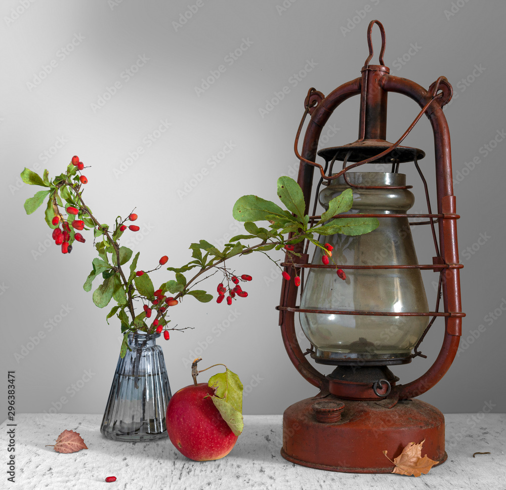 Still life with apple, sprigs of barberry with berries and an old kerosene lamp. Vintage