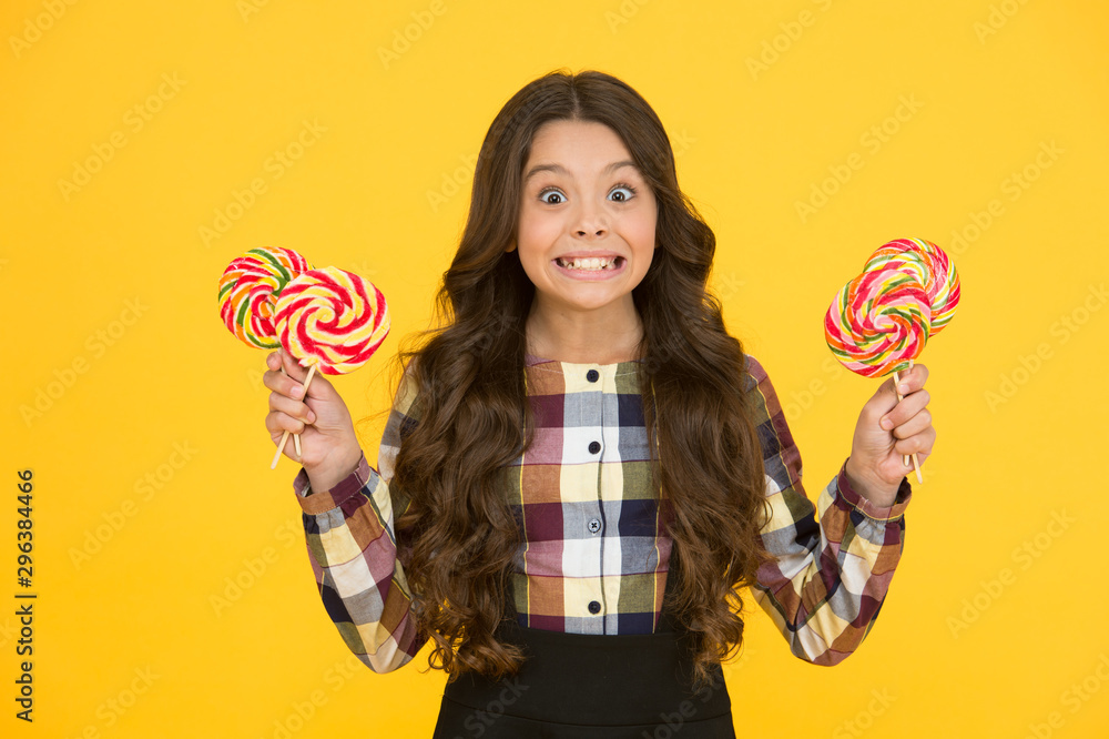 Always eat dessert first. Happy small schoolchild hold candy dessert on sticks. Little girl smile with lollipops. Sweet dessert. School snack. Her favorite rainbow swirl dessert