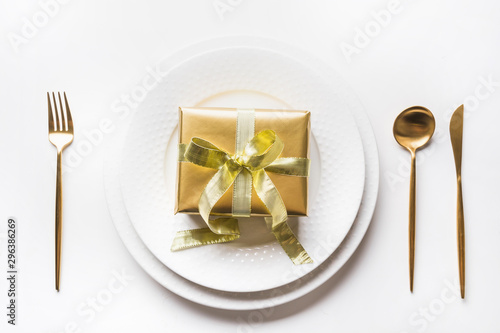 Christmas table setting with golden gift box, silverware on white background. Celebration,Love, Holiday. Top view.