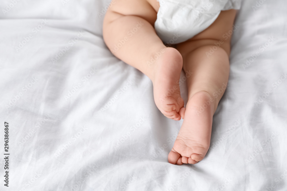 Cute little baby lying on bed, closeup of legs. Space for text Cute little baby lying on bed, closeup of legs. Space for text