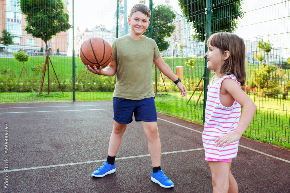 Children play basketball on a city playground.  Streetball basketball game with two players, outdoor city basketball court.