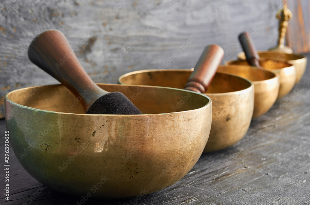 Tibetan singing bowls with sticks on the dark background - music instruments for meditation, relaxation after yoga practice and healing massage Tibetan singing bowls with sticks on the dark background - music instruments for meditation, relaxation after yoga practice and healing massage