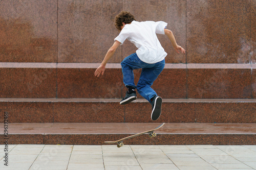Young skateboarder performs a trick on a city street in autumn day. Young man is jumping. Extreme sports is very popular among youth.