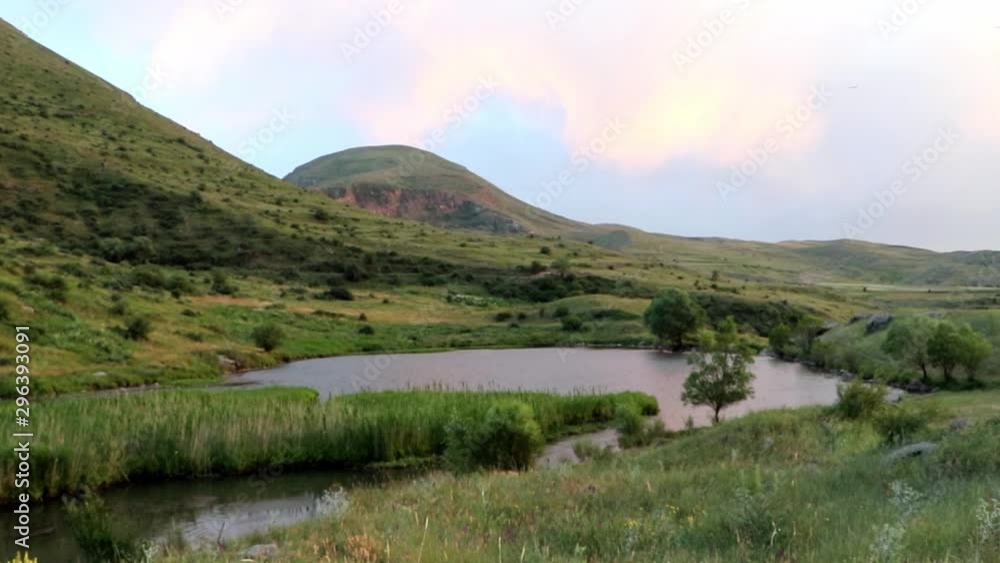 A majestic scene of a pond among green foothills of a countryside. A majestic scene of a pond among green foothills of a countryside.