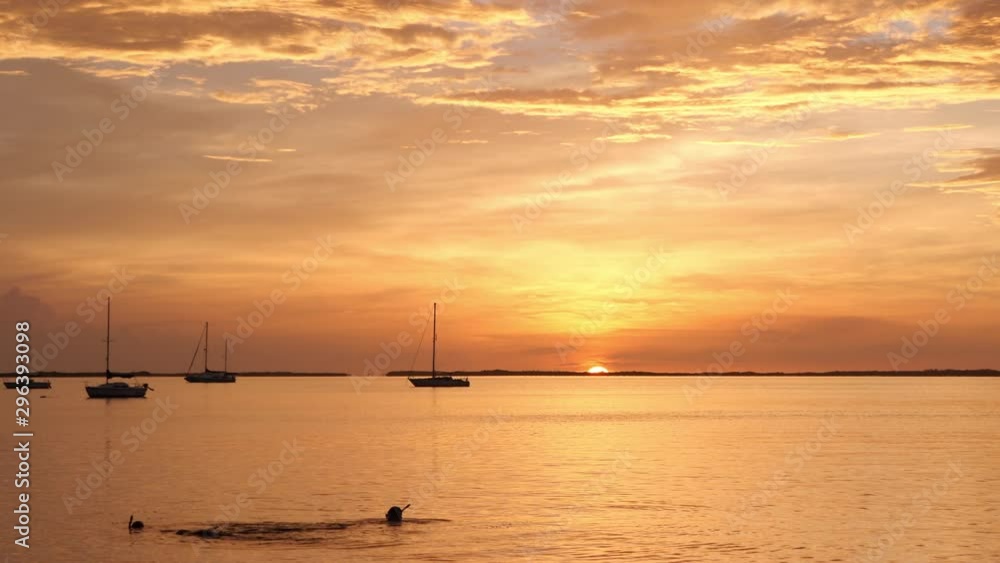 Couple snorkeling in the sunset in Gulf Of Mexico at Key West, Florida. Behind them can be seen the silhouettes of sailboats with lowered sail. The sun is going down over the horizon. Couple snorkeling in the sunset in Gulf Of Mexico at Key West, Florida. Behind them can be seen the silhouettes of sailboats with lowered sail. The sun is going down over the horizon.
