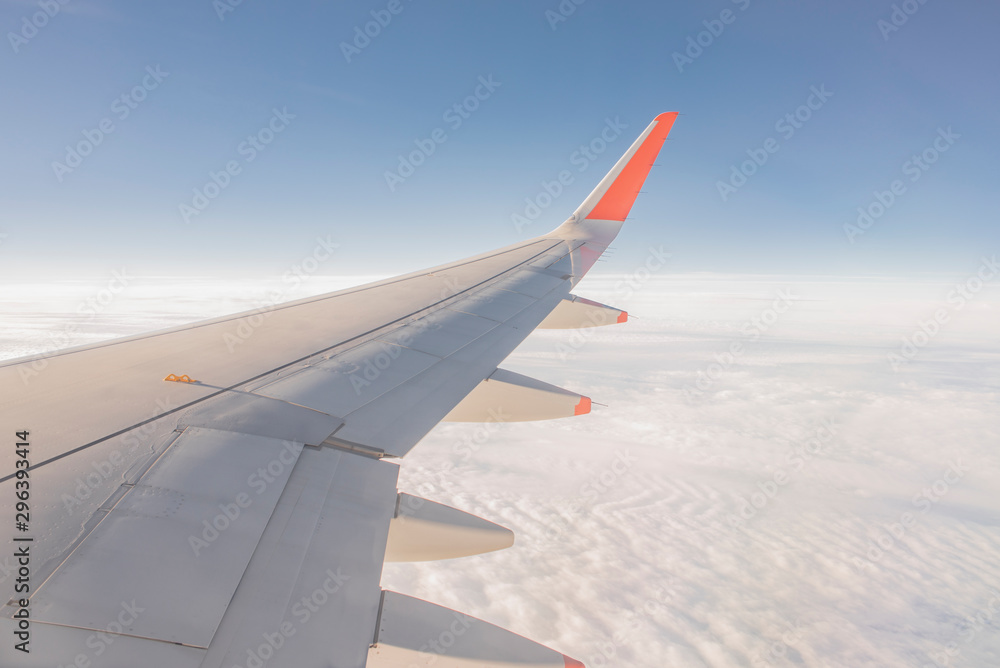Obraz premium Wing of the plane outside of the window. Airplane above the sky. Airplane above the cloud. Looking outside the airplane window.