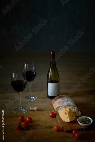 Fototapeta Naklejka Na Ścianę i Meble -  Wine and snacks on a wooden table.black background. dinner for two