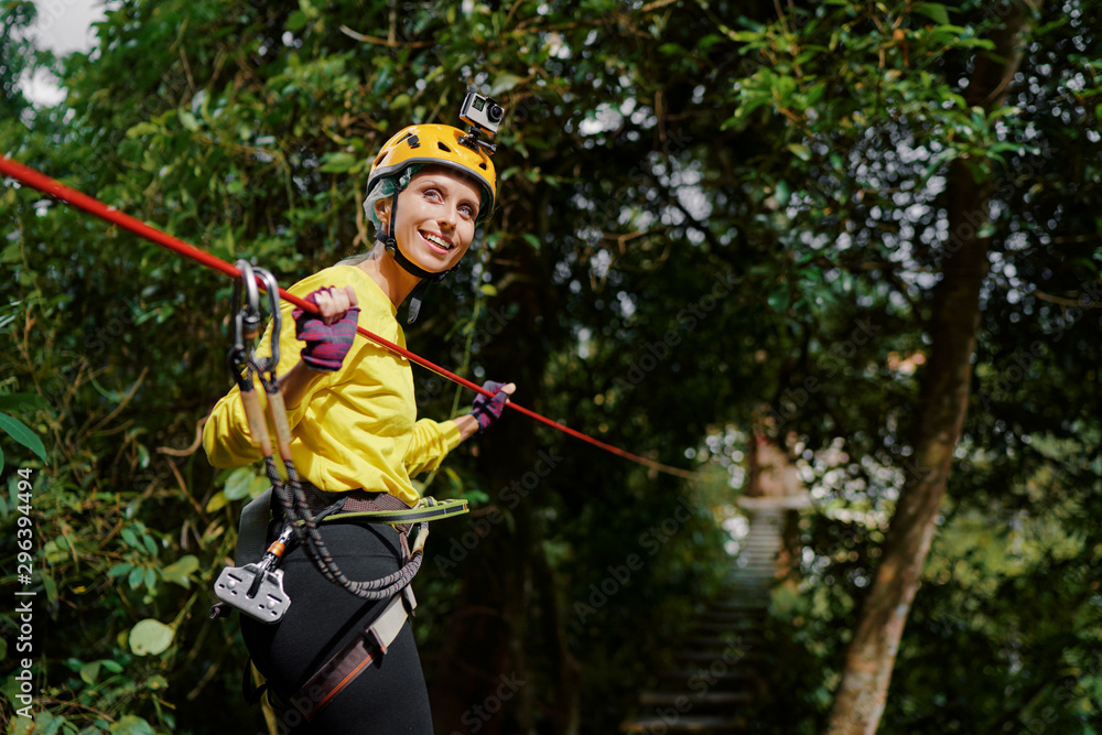 Young woman with climbing gear in an adventure extreme park climbing or passing on the rope road. Young woman with climbing gear in an adventure extreme park climbing or passing on the rope road.