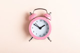 Little pink alarm clock on a pink background