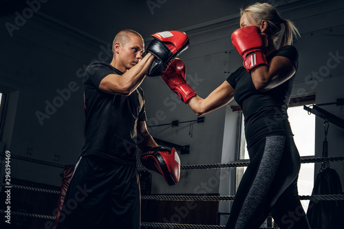 Sportive blond woman has boxing training with her experienced trainer.