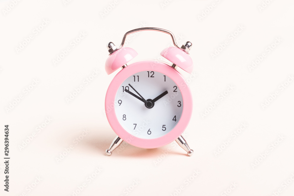 Little pink alarm clock on a pink background Little pink alarm clock on a pink background