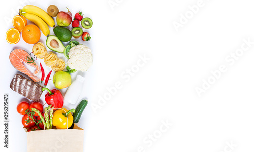 Healthy food background. Healthy food in paper bag fish, pasta, vegetables, fruits, milk, bread on white background. Shopping food supermarket, healthy eating, nutrition plan concept. Copy space