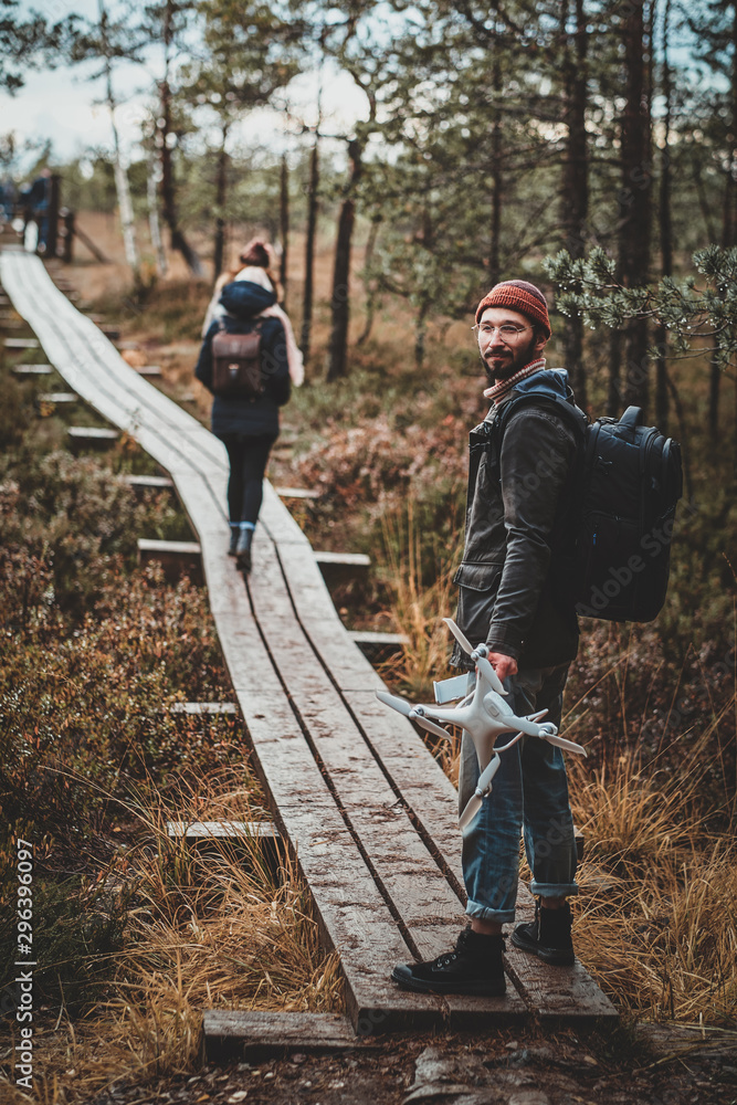 Trendy bearded student is enjoying autumn walk with his drone at the park. Trendy bearded student is enjoying autumn walk with his drone at the park.