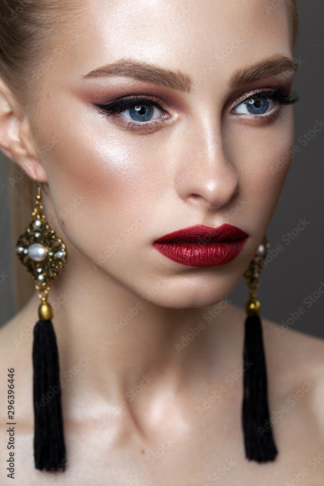 Beautiful young blond model with professional makeup, perfect skin, long fashion earrings