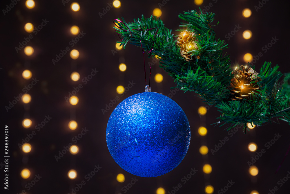 There is blue ball on the green xmas tree branch. There are glowing lights/bokeh and on the background. Merry Christmas. Happy New Year 2020. There is blue ball on the green xmas tree branch. There are glowing lights/bokeh and on the background. Merry Christmas. Happy New Year 2020.