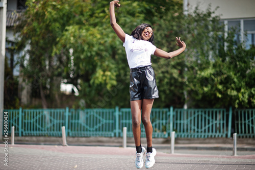 African american dark skinned slim model posed in a black leather shorts and white t-shirt. © AS Photo Family