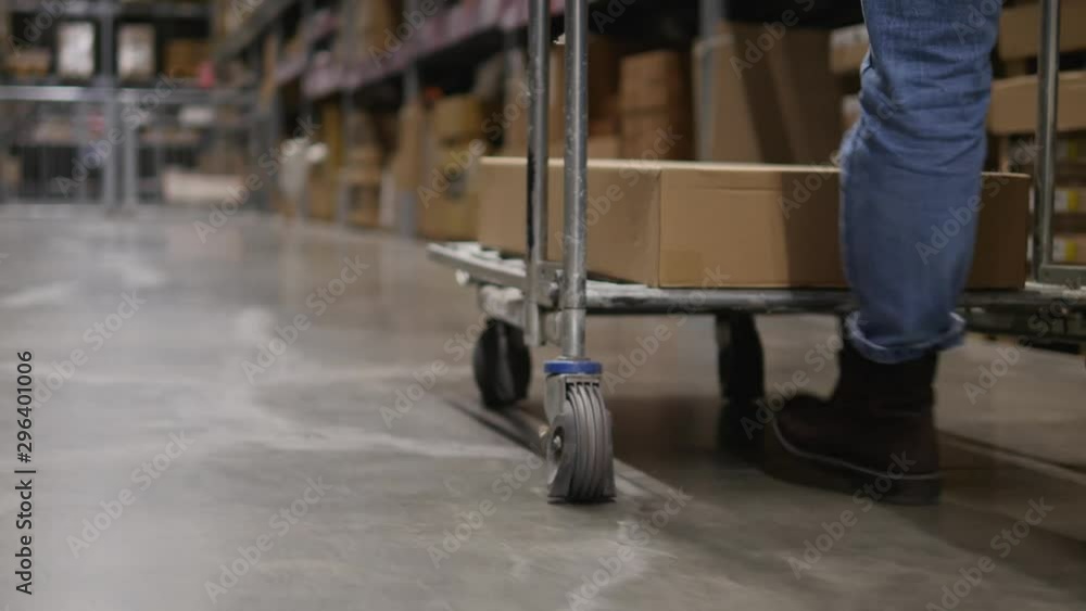 Legs closeup carry a cart with a box. Close-up of a cart with a box in motion Legs closeup carry a cart with a box. Close-up of a cart with a box in motion