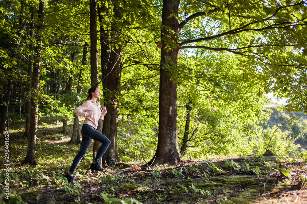 Young girl jogging in the woods on a sunny morning.